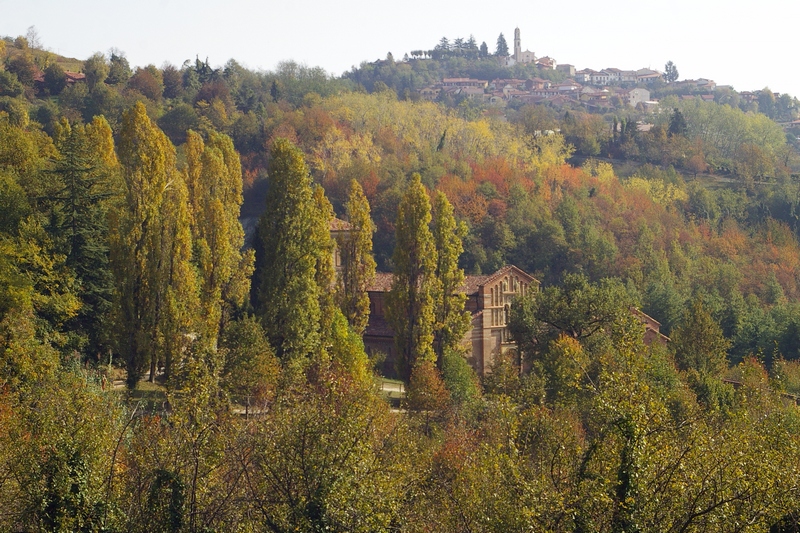 Veduta della facciata anteriore della Canonica di Santa Maria di Vezzolano, immersa nella fitta vegetazione boschiva dell Alto Astigiano con sullo sfondo l abitato di Albugnano.